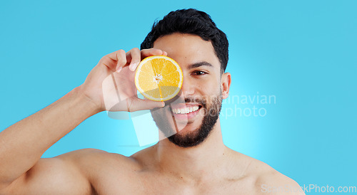 Image of Orange, skincare or portrait of man in studio for vitamin C, natural cosmetics or healthy diet on blue background. Fruit, beauty and model face with citrus skin detox, cleaning or wellness nutrition