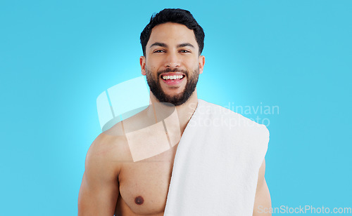Image of Shower, portrait and happy man in studio with towel for body care, wellness or grooming on blue background. Face, smile and model smile for beauty results, treatment or glow from bathroom routine