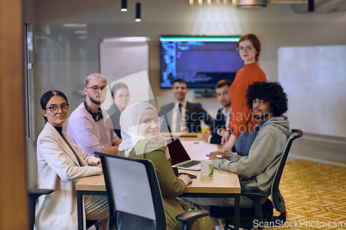 Image of A diverse team of business experts in a modern glass office, attentively listening to a colleague's presentation, fostering collaboration and innovation.