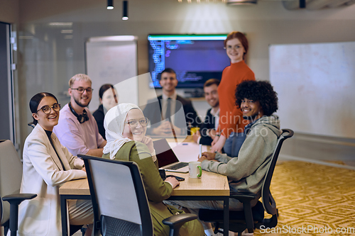 Image of A diverse team of business experts in a modern glass office, attentively listening to a colleague's presentation, fostering collaboration and innovation.