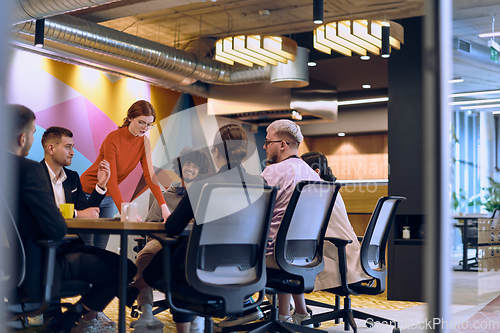 Image of A diverse team of business experts in a modern glass office, attentively listening to a colleague's presentation, fostering collaboration and innovation.