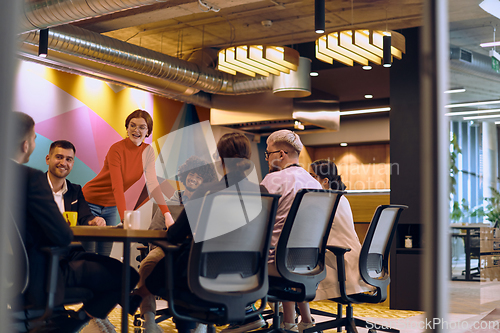 Image of A diverse team of business experts in a modern glass office, attentively listening to a colleague's presentation, fostering collaboration and innovation.