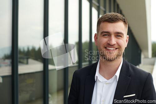 Image of A CEO dressed in a sleek black suit stands confidently at the entrance of a modern corporate building, awaiting the start of the workday in the bustling urban environment.