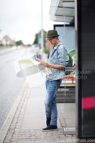 Image of Man, journey and bus stop with map, travel and adventure by commute, transportation and planning for trip. Male person, information and guide for direction, navigation and vacation or earphones