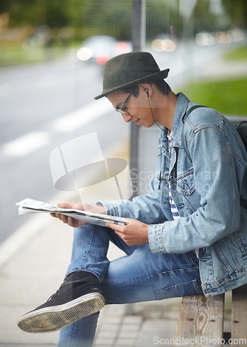 Image of Man, commute and bus stop with newspaper, travel and adventure on journey, transportation and reading for trip. Male person, earphones and headlines or music, smile and happy for article in outdoors