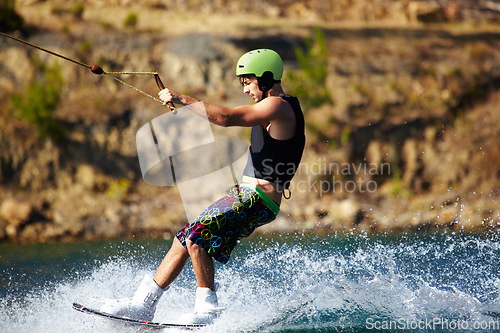 Image of Man, wakeboarding outdoor and water with helmet, sport and fitness for speed in summer sunshine. Person, athlete and ski with rope for safety on lake, sea or river for training, exercise and waves