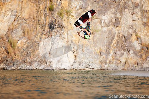 Image of Man, wakeboarding and lake for jump in air, sport and fitness for speed in summer sunshine. Person, athlete and ski with rope for safety on ocean, sea or river for training, exercise or free on waves