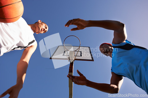 Image of Men, player and basketball match at outdoor court or low angle of challenge team, dunk on rival. Male people, hoop and score point in summer park at fitness game or competition, athlete on blue sky