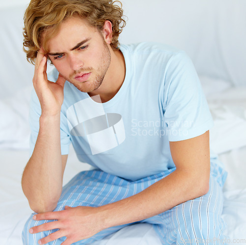 Image of Stress, thinking and exhausted with a man on his bed in the morning to wake up feeling moody. Depression, mental health or burnout with a tired young person alone in the bedroom of his apartment
