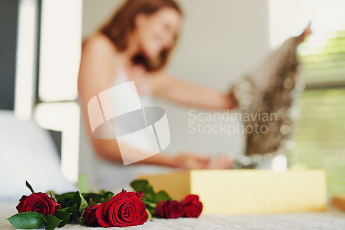 Image of Woman, roses and box with gift in bedroom on birthday, celebration and valentines day event in home. Girl, dress and fashion with bouquet, flowers and floral present with thinking on bed in house