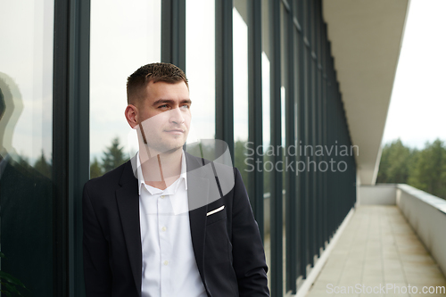 Image of A CEO dressed in a sleek black suit stands confidently at the entrance of a modern corporate building, awaiting the start of the workday in the bustling urban environment.