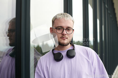 Image of In front of a modern glass building, a young, blond influencer strikes a confident pose, epitomizing urban glamour and style in the heart of the city