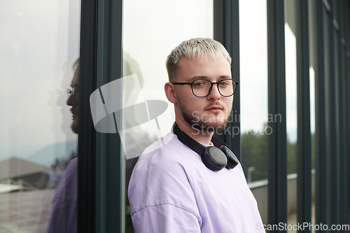 Image of In front of a modern glass building, a young, blond influencer strikes a confident pose, epitomizing urban glamour and style in the heart of the city