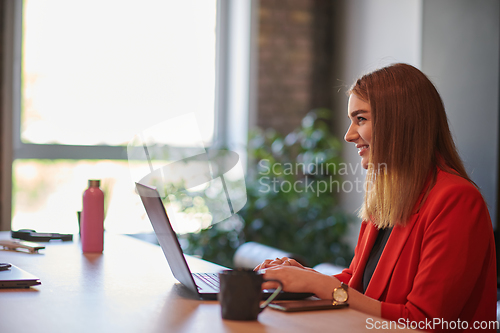 Image of In a contemporary office setting, a young businesswoman is focused on her laptop, displaying dedication and efficiency in her work