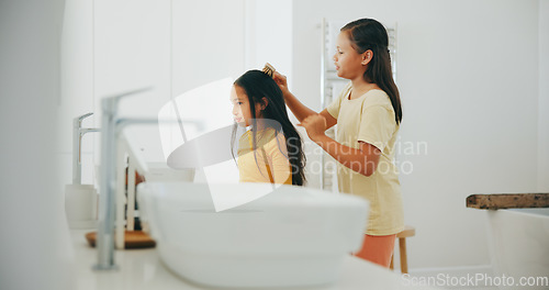 Image of Family, bathroom and a girl brushing the hair of her sister in their home for morning routine or care. Kids, beauty or haircare with a young child and helping sibling in their apartment for love