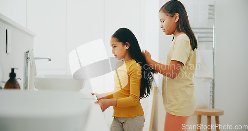 Image of Family, bathroom and a girl brushing the hair of her sister in their home for morning routine or care. Kids, beauty or haircare with a young female child and sibling in their apartment for hygiene