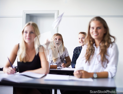 Image of Paper, plane and students in class at school with fun, joke or people in education. Teenagers, classroom and learning at academy campus with funny friends, surprise and throwing prank airplane