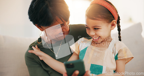 Image of Child, grandmother and cellphone laugh on sofa or online connection, games or bonding. Kid, old woman and smile for social media or funny joke embrace on couch together relax, love or trust safety