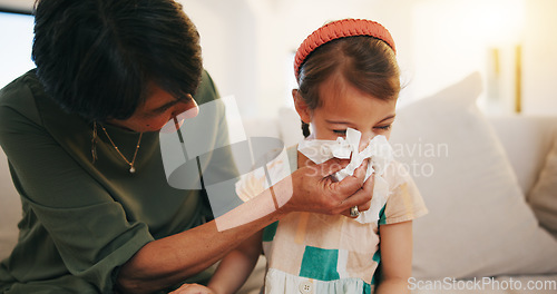 Image of Grandmother, sick kid and sneeze in home living room for allergy, covid or virus on sofa. Grandma, girl child and tissue for cold, flu and bacteria, disease and care or mature woman help blowing nose