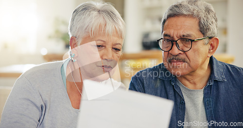 Image of Senior couple, bills and reading paperwork in home for budget, planning investment and financial assets. Man, woman and discussion with documents for banking, retirement savings and insurance policy