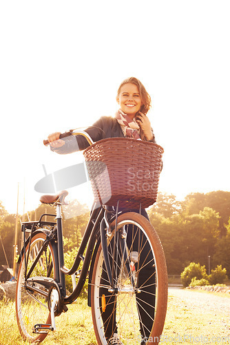 Image of Countryside, nature and portrait of happy woman with bicycle, adventure or travel in morning. Summer, smile and bike with a basket at sunset and person in sunshine with transportation for cycling