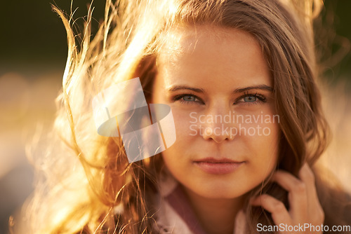 Image of Serious, woman and portrait in nature at sunset in autumn, spring or environment in summer. Calm, face and girl relax with hair in the wind with golden, sunshine and light at sunrise in morning