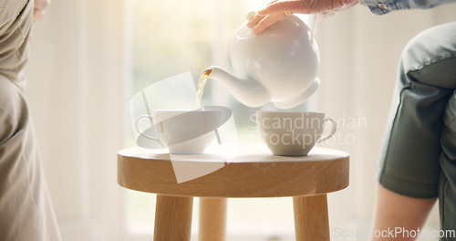 Image of Pour, pot and hands with tea cup in morning, home and closeup on drink, steam and table. Hot, beverage and person with hospitality, service and drinking in the afternoon with guest in living room