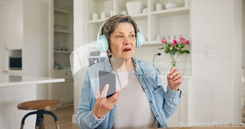 Image of Music, headphones and senior woman with phone in a kitchen for streaming, album or track at home. Smartphone, app and elderly lady person with earphones for online audio, radio or podcast in a house