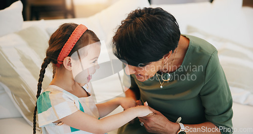 Image of Happy, child and grandmother laughing on couch together with love, care and holding hands in lounge. Family, support and senior woman with girl in living room bonding together with secret or joke