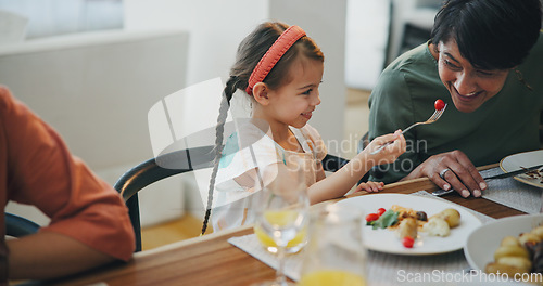 Image of Food, family and a girl feeding her grandmother at a dining room table while in their home for a visit together. Love, smile and a senior woman eating a meal with her happy grandchild in an apartment