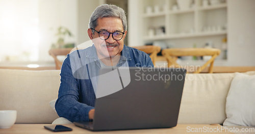 Image of Elderly, man and smile for laptop living room on sofa for typing, email or message for communication. Senior person, looking at screen and glasses with technology, internet or web for work from home