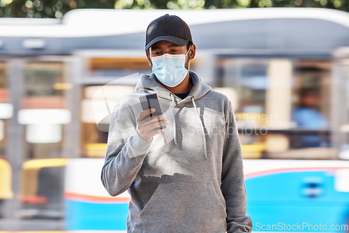 Image of Man in city with mask, phone and travel in morning at bus stop, checking service schedule or social media. Public transport safety in covid, urban commute and person in street with smartphone app.