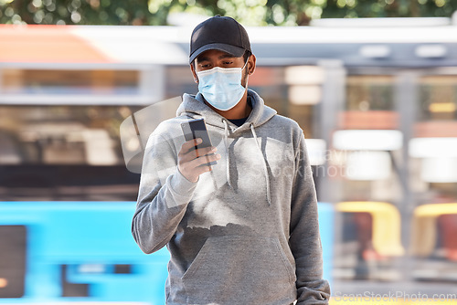 Image of Man in city with mask, phone and morning travel at bus stop, checking service schedule or social media. Public transport safety in covid, urban commute and person in street with smartphone connection