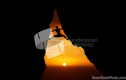 Image of Mountain, sunset and hiking with the silhouette of a man climbing a cliff or rock outdoor in nature. Sun, horizon and sky with a climber outside for exercise, workout and training in the evening