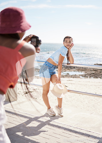 Image of Beach, model and photo shoot with a woman outdoor on the promenade for a photograph with the sea, ocean or beautiful beach view. Fashion, photographer and summer with an attractive young female