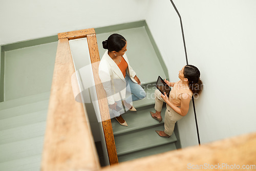 Image of Colleagues discuss, plan and share ideas on a staircase at work in a startup business. Overhead of Businesswomen talking, chatting and socializing on a stairway during a break at a corporate job