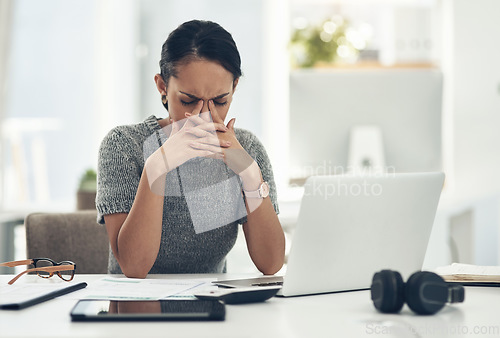 Image of Stress, anxiety and worry with a businesswoman feeling negative, overworked and overwhelmed while suffering from a headache or migraine. Young female working on a laptop at her desk in the office