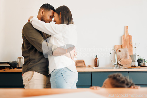 Image of Cosy couple hugging, romance and affection in a modern kitchen with small child looking at them. Loving, young and parents, mom and dad embrace, excited by the future of their growing family