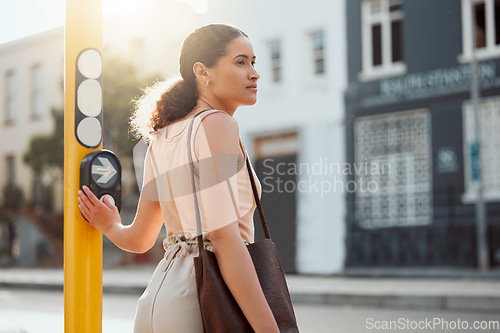 Image of Attractive female pedestrian ready to cross the street, waiting for green light and pressing the button at a crossing Young city woman on a morning walk to work, standing and looking out for traffic.