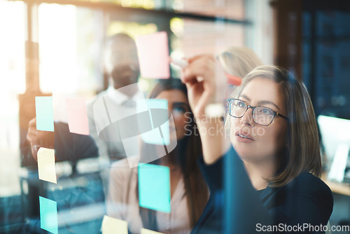 Image of Marketing leader planning and writing on sticky notes on wall while support and sharing vision or idea. Diverse group of creative office business people meeting together to market new startup company