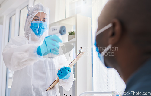 Image of Healthcare worker, checking the temperature of male covid patient for safety against virus pandemic, wearing protective suit. Medical doctor in a hazmat suit, using a thermometer to prevent outbreak