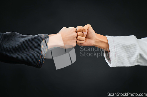 Image of Teamwork, respect and discipline with hands fist bumping before a fight, match or mma competition. Closeup of two athletes greeting before combat sport and self defense against a black background