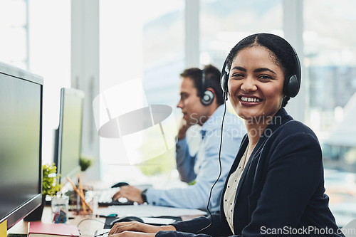 Image of Portrait of happy call center agent working in a busy office, assisting clients and providing good customer service. Young, smiling and cheerful professional excited to offer support or help on calls