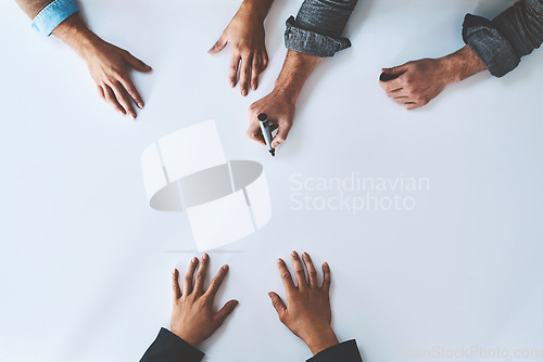 Image of Business people writing on white paper in meeting, planning a marketing strategy and writing creative ideas together from above. Top view of hands of team of designers drawing a design on blank page