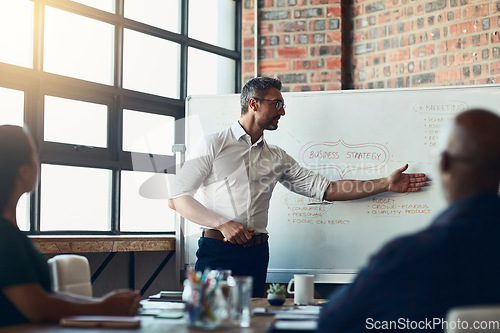 Image of Take a look right here. Businessman doing a presentation in a meeting planning the company growth strategy in an office. Serious male entrepreneur briefing his team on the startup mission and vision.