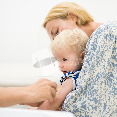 Image of Child beeing vaccinated by pediatrician in presence of his mother. Preventive vaccination against Diphtheria, whooping cough, tetanus, hepatitis, haemophilus influenzae, pneumococcus, poliomyelitis