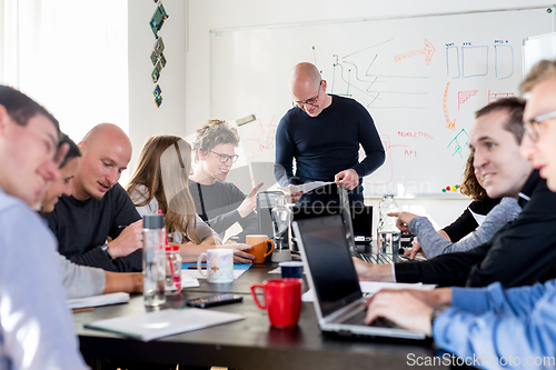 Image of Startup business and entrepreneurship problem solving. Young AI programmers and IT software developers team brainstorming and programming on desktop computer in startup company share office space.