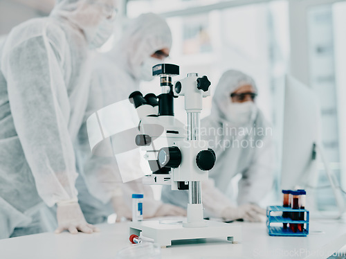 Image of Sterile, white and modern room with a closeup of a microscope and medical scientists or group conducting research for corona. Clinical and bright laboratory with doctors working on a blood sample.