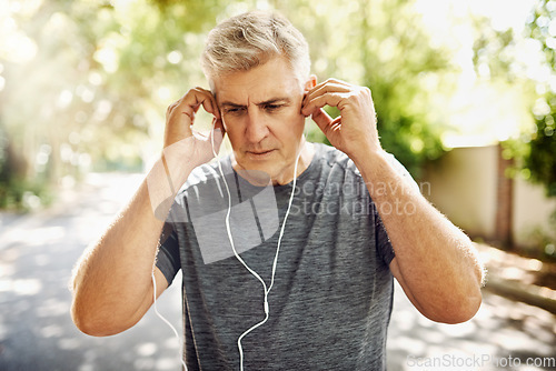 Image of Fit, mature and healthy or sporty athlete resting after morning run, listening to music outdoors with earphones. Male jogger about to exercise or do cardio training workout for wellness lifestyle.