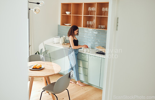 Image of Young woman making tea, coffee or morning drink in a kitchen while relaxing at home. Female enjoying, preparing and drinking a beverage for a cosy, comfortable and peaceful, day or breakfast